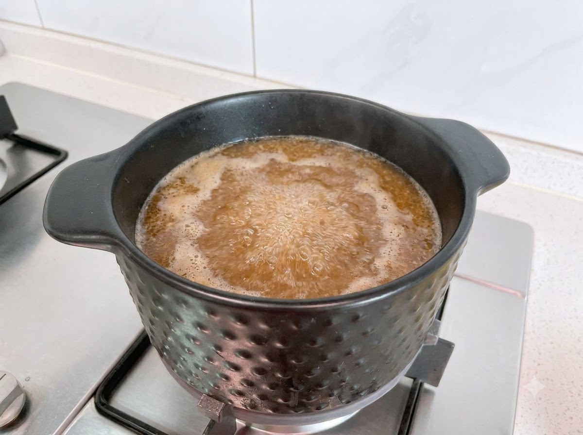 Raw pork pieces being cooked in a bubbling pot of soybean paste soup.