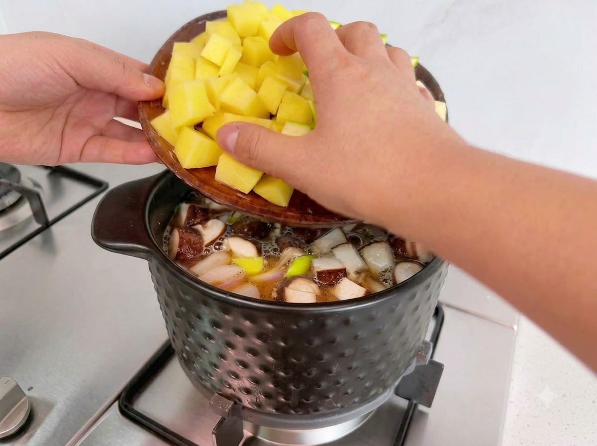 Chopped yellow potatoes and zucchini being added from a wooden tray into the cooking pot.