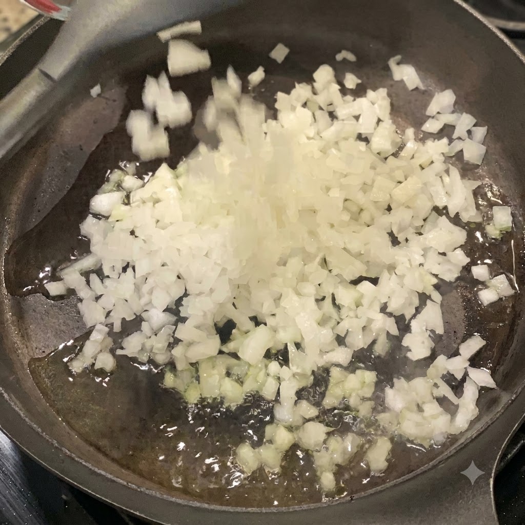 A handful of freshly chopped white onions being dropped into an oiled frying pan on the stove.
