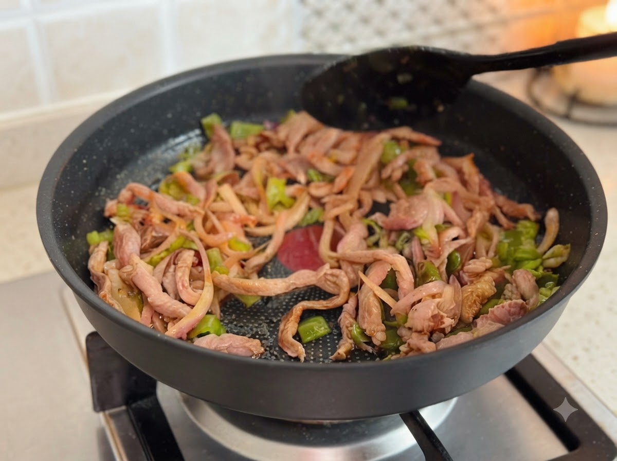 Cheese slices melting on top of the cooked meat and vegetable mixture inside a frying pan.