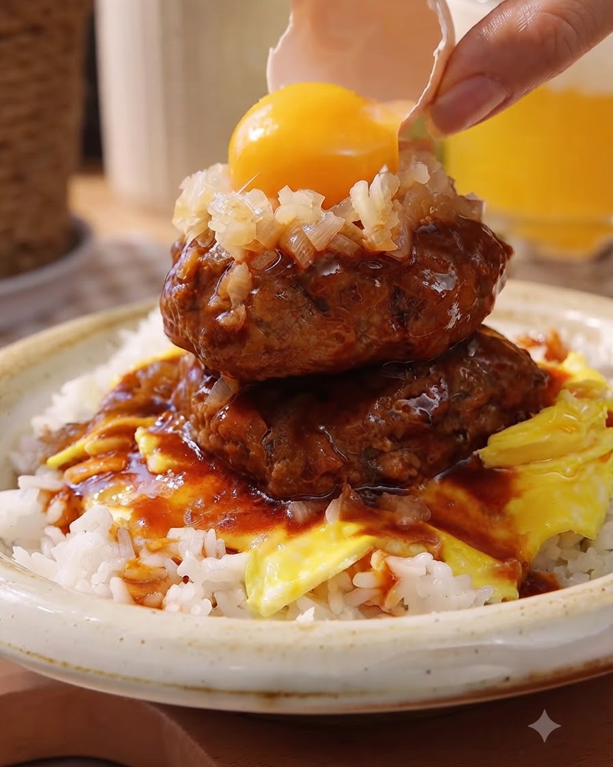 A bright yellow egg yolk being dropped from a broken eggshell onto a bed of chopped onions atop stacked meat patties.