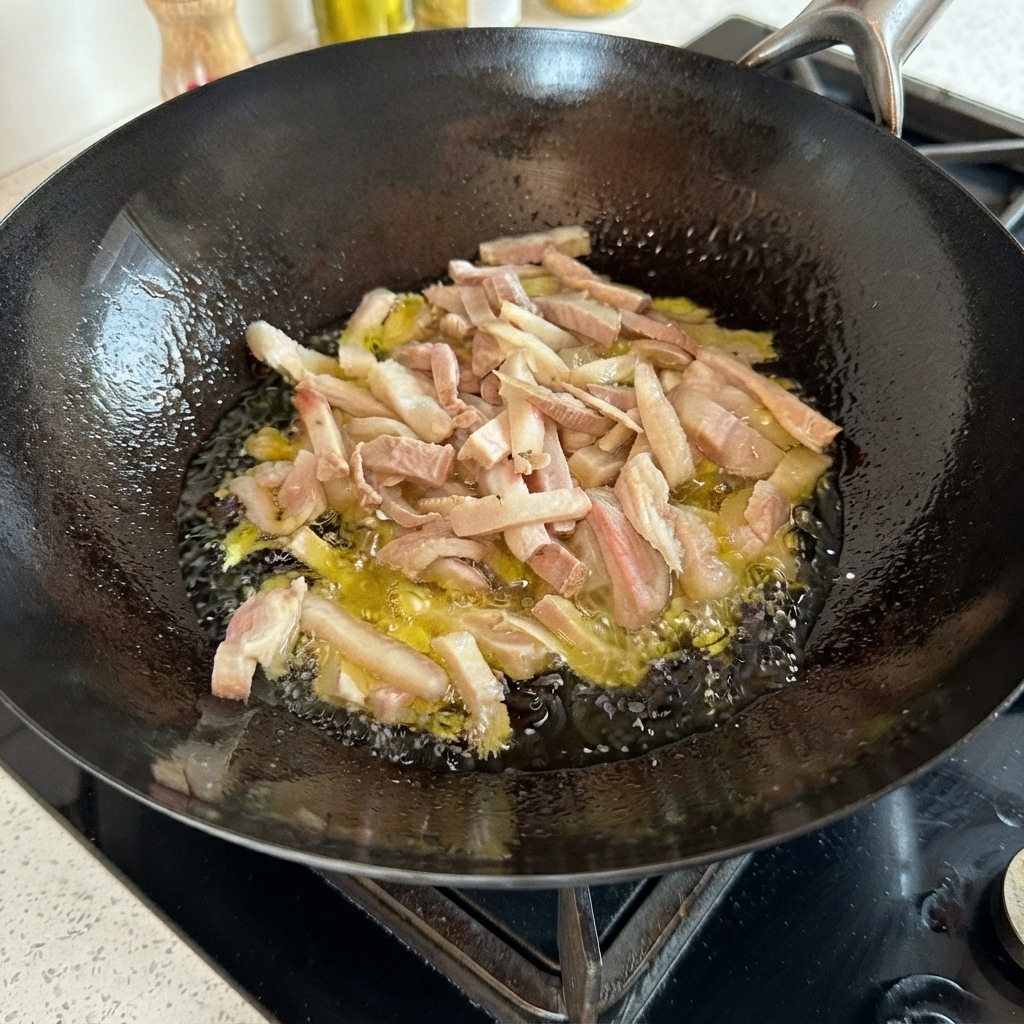 Pork strips sizzling in hot oil inside a black wok.