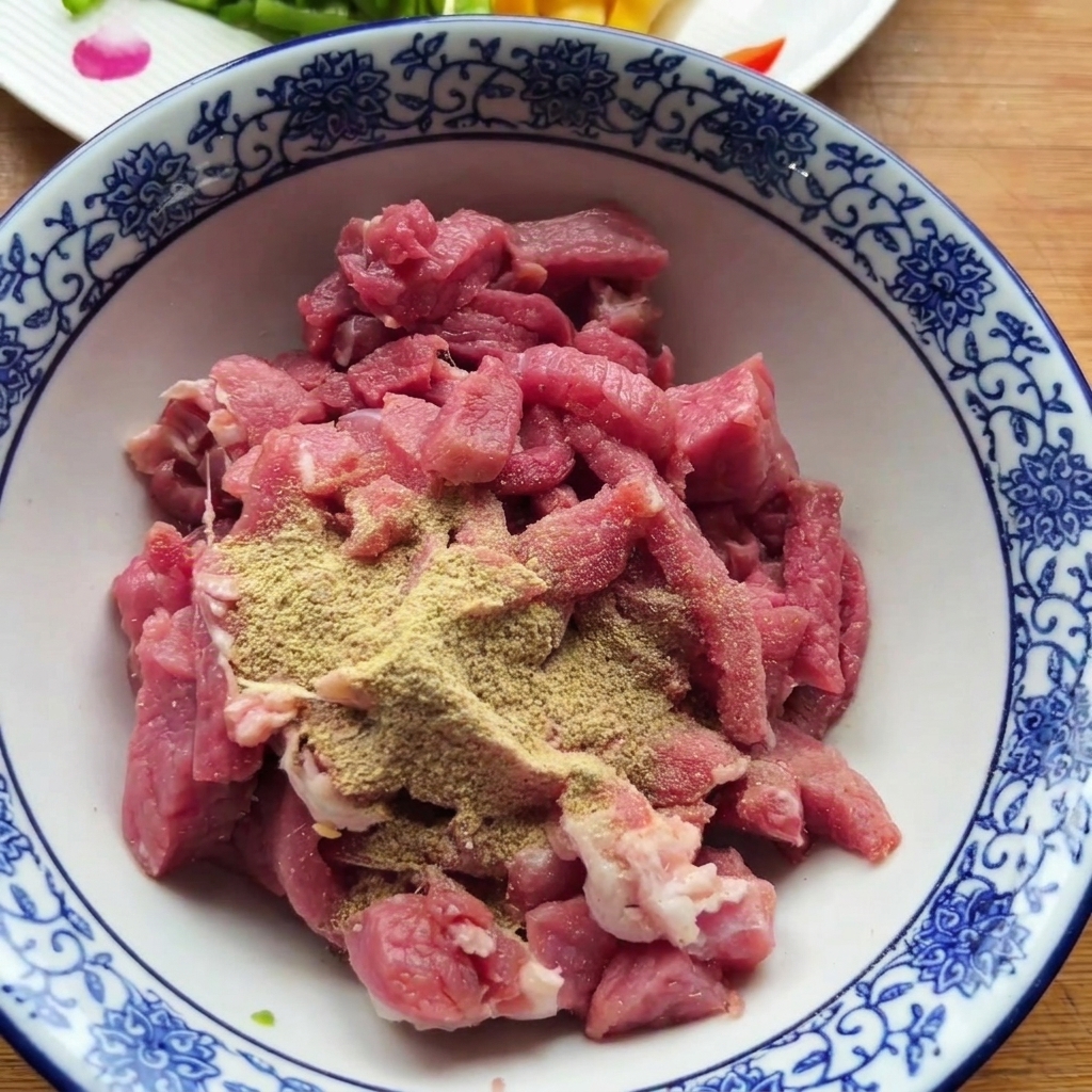 Raw beef pieces in a patterned bowl topped with dry powdered spices.